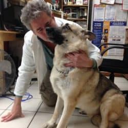 A woman in a lab coat petting a dog.